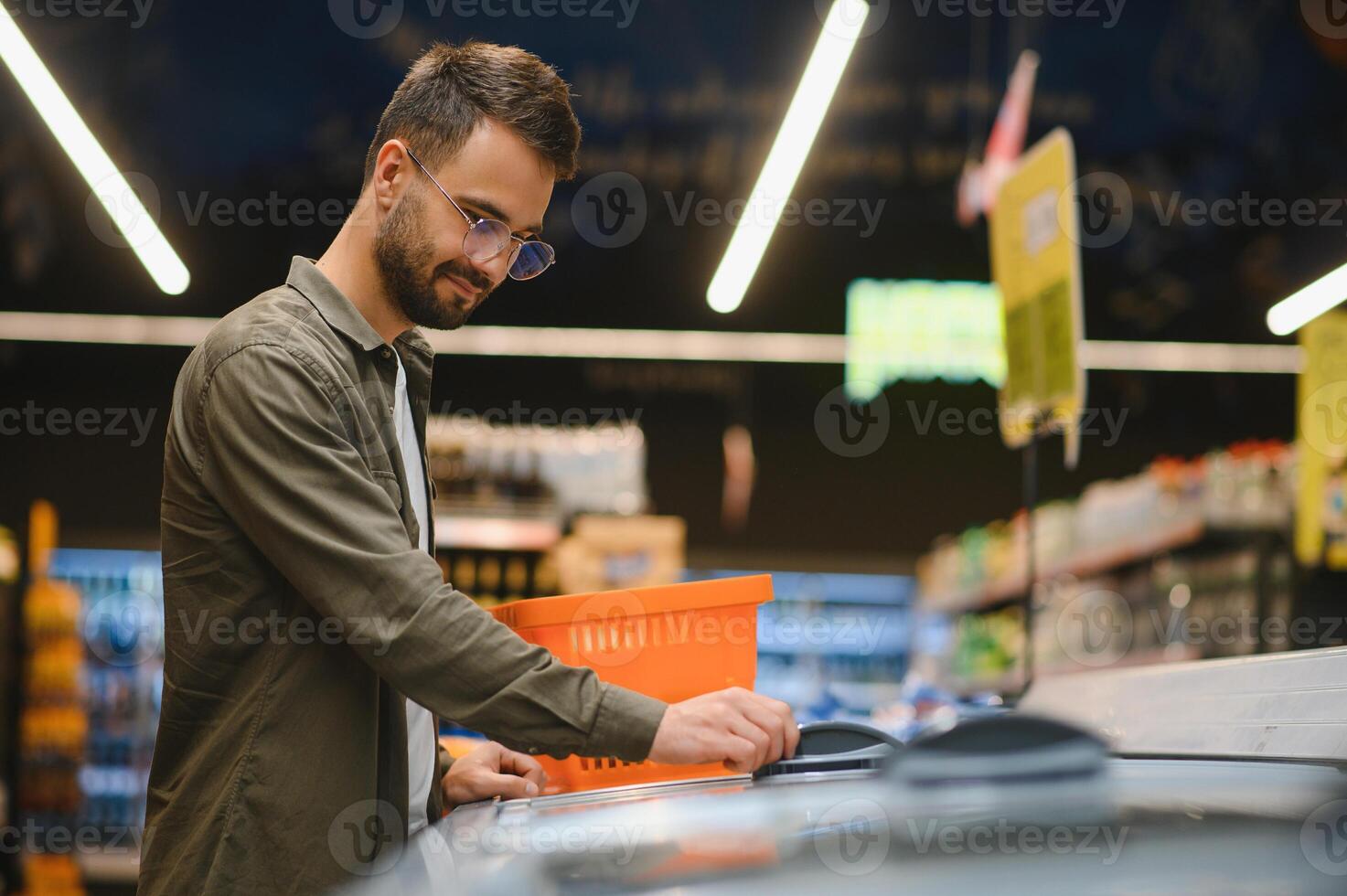 joven hombre comprando comestibles a el supermercado. otro clientes en antecedentes. consumismo concepto. foto