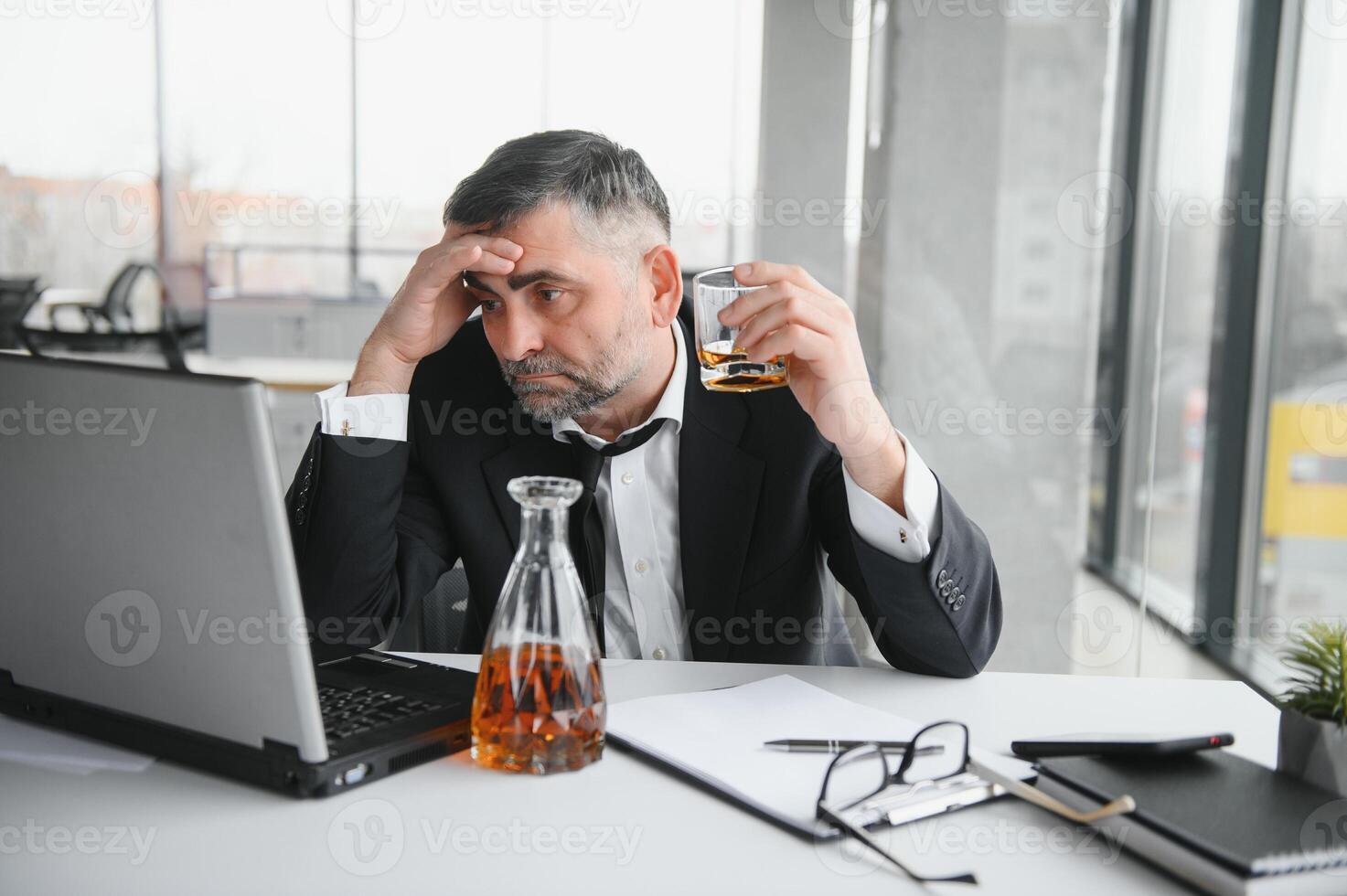 Old business man is drinking alchool at the office photo