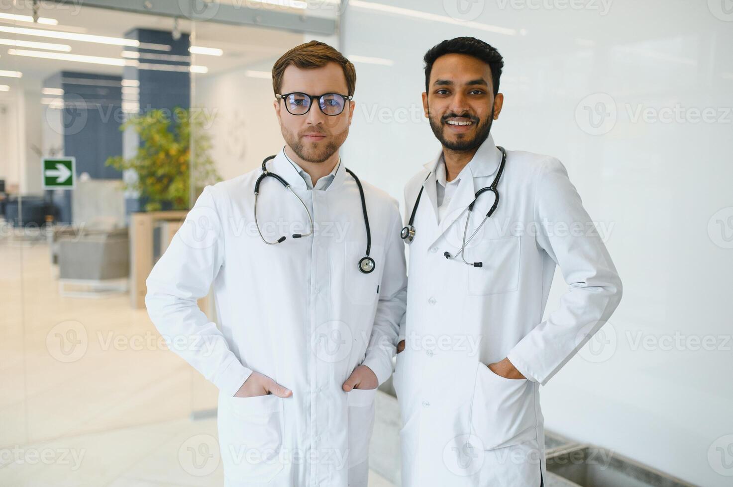 un indio médico y un europeo médico estar juntos en un hospital vestíbulo. foto