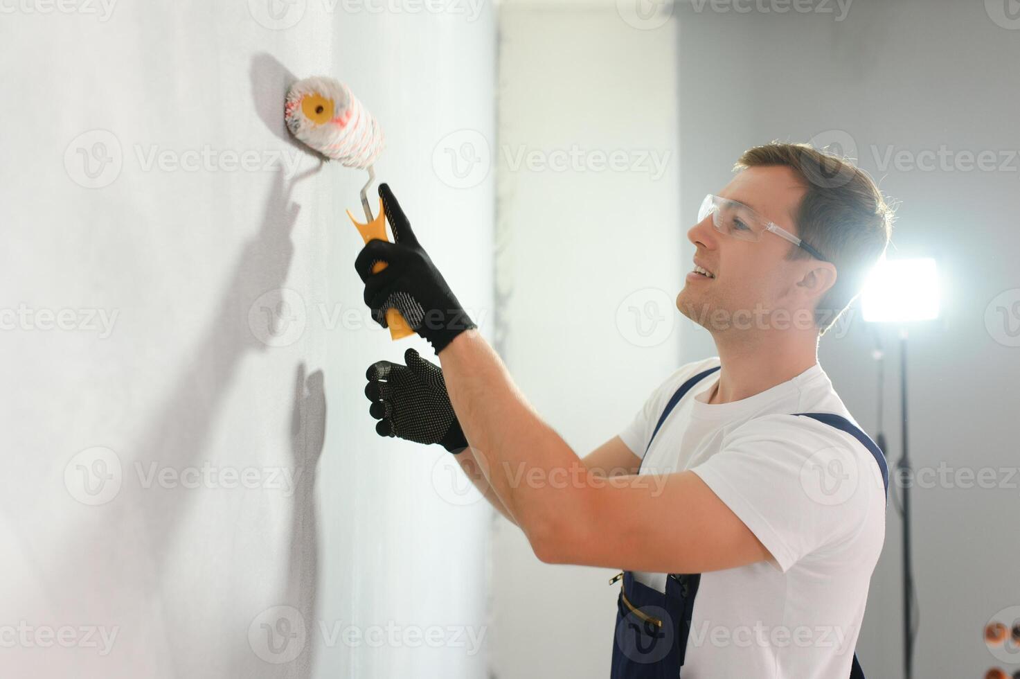 Young worker painting wall in room photo
