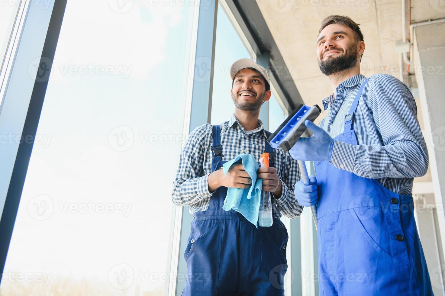 multiétnico profesional limpiadores en uniforme Lavado grande ventanas en oficina foto