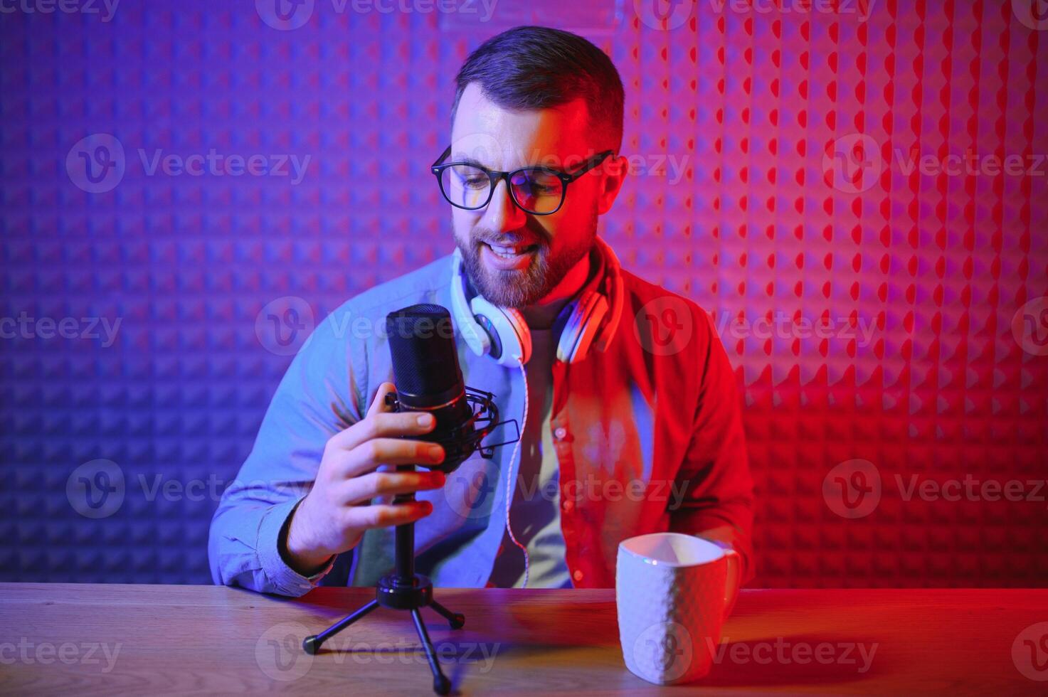 Young man recording or streaming podcast using microphone at his small broadcast studio. Content creator. photo