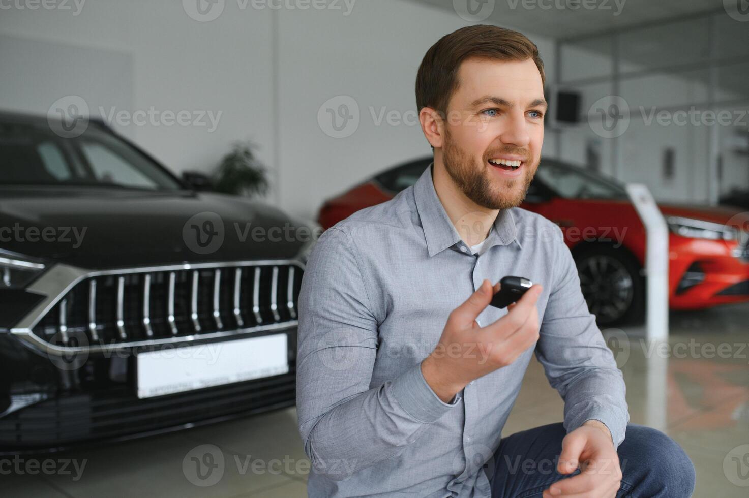 Yes, that's my new car. Customer in car dealership. Young man with keys in hand. photo