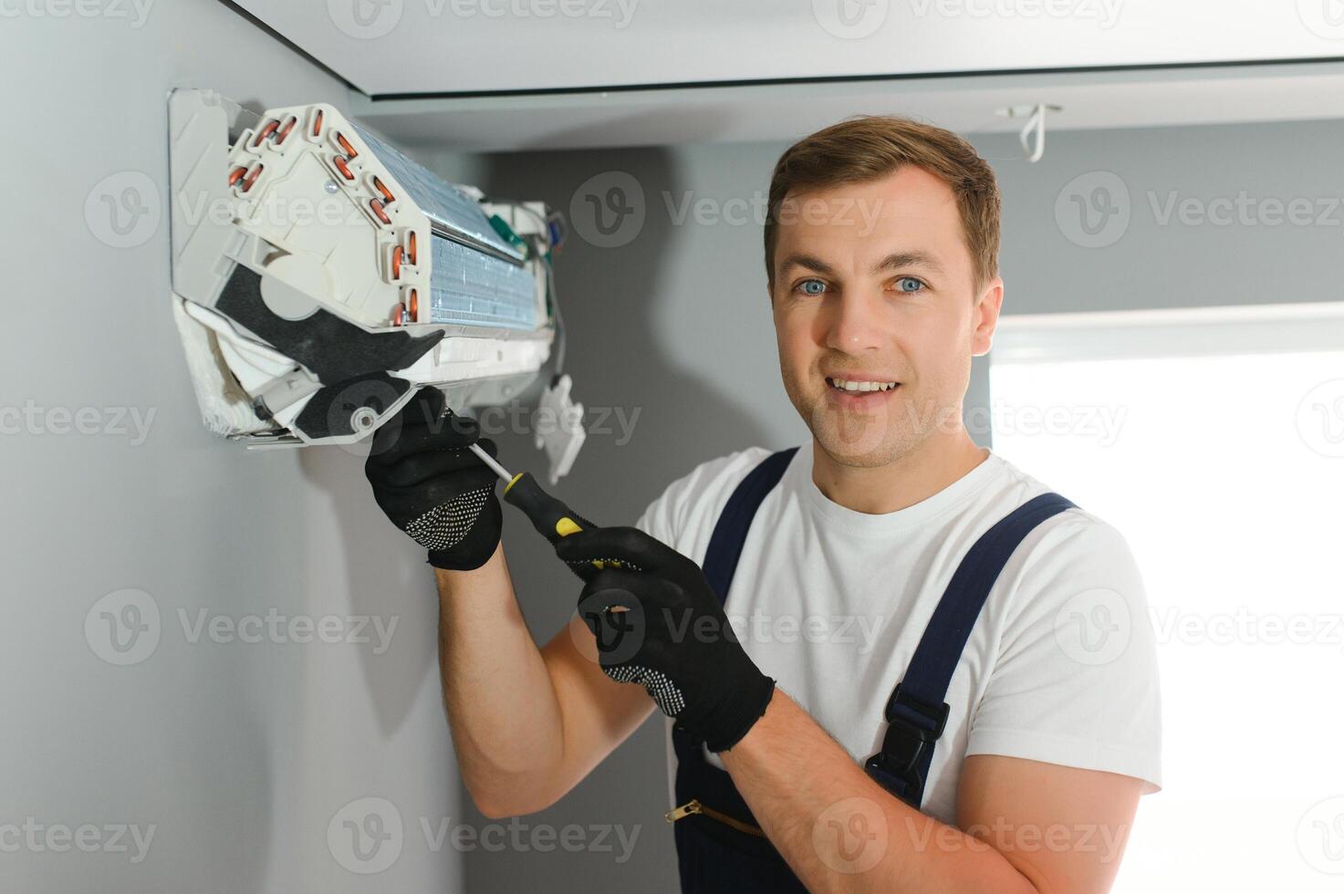 Technician repairing air conditioner on the wall photo