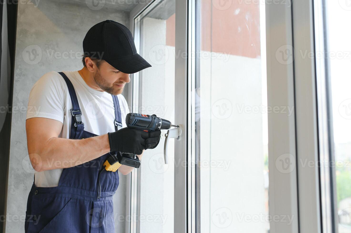 Workman in overalls installing or adjusting plastic windows in the living room at home photo