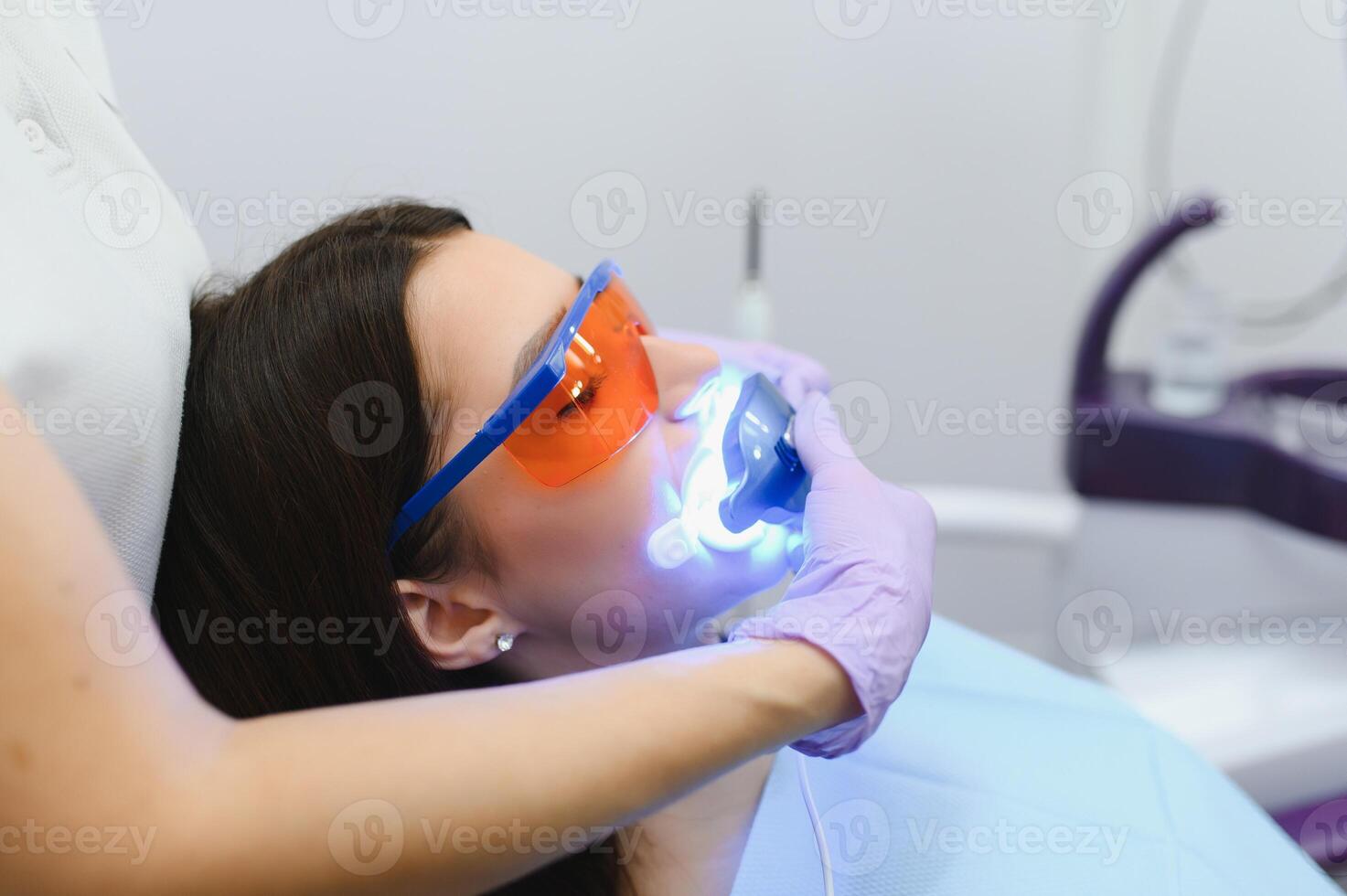 Teeth whitening for woman. Bleaching of the teeth at dentist clinic. photo