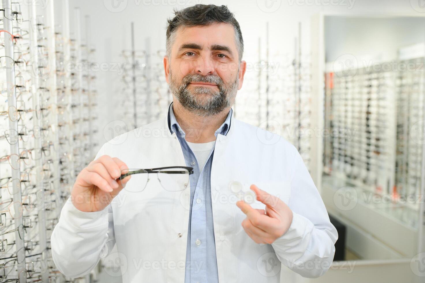 Eye doctor choosing between eyeglasses and lenses standing in front of the eye chart in the cabinet photo