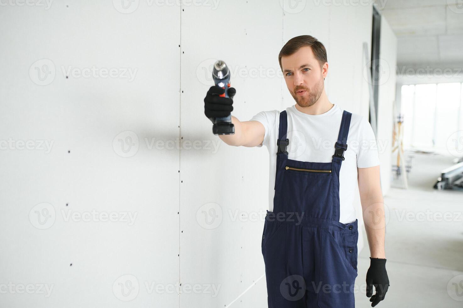 Worker builder installs plasterboard drywall at a construction photo