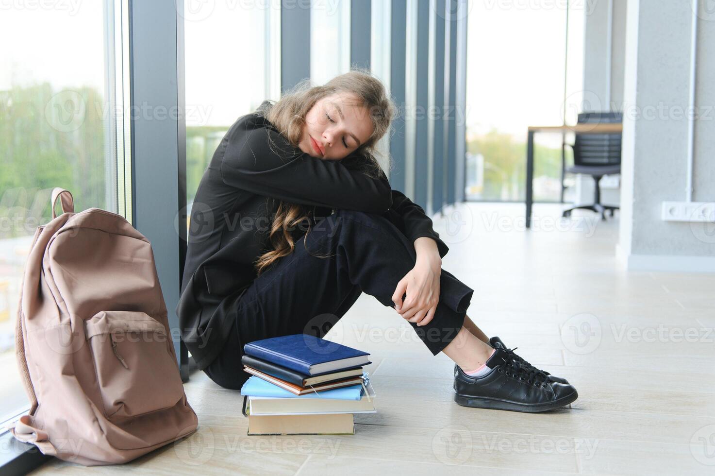 Lonely sad schoolgirl while all her classmates ignored her. Social exclusion problem. Bullying at school concept. photo