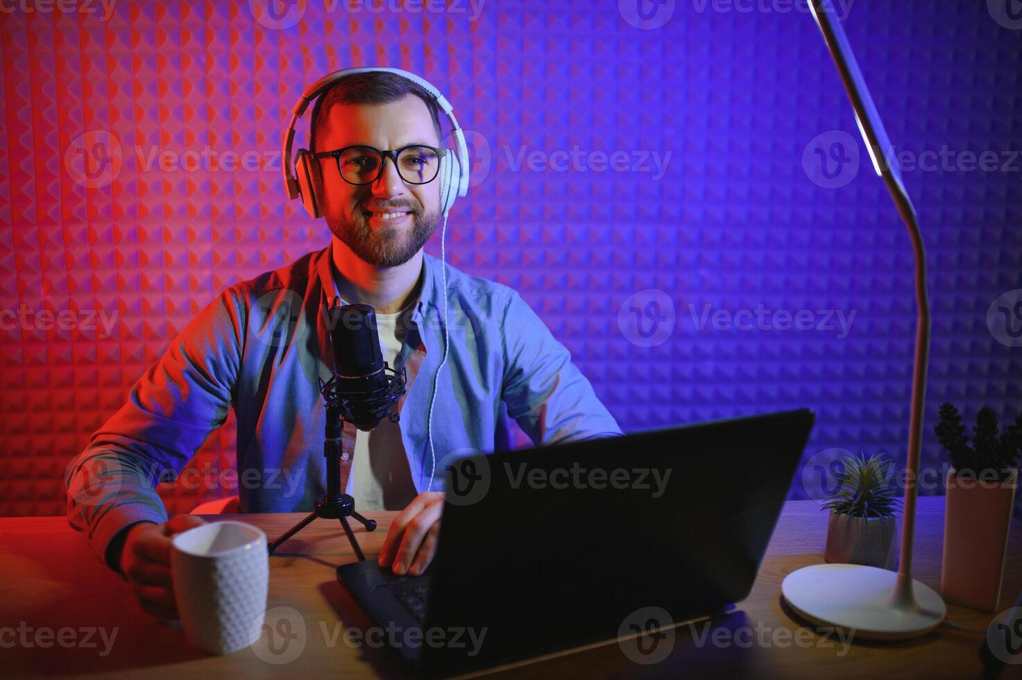 joven hombre grabación o transmisión podcast utilizando micrófono a su pequeño transmitir estudio. contenido creador. foto