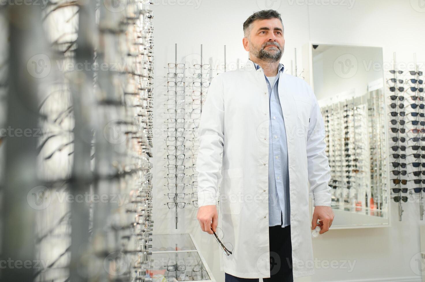 retrato de un hermoso oftalmólogo en frente de el escaparate con los anteojos en el hospital. foto