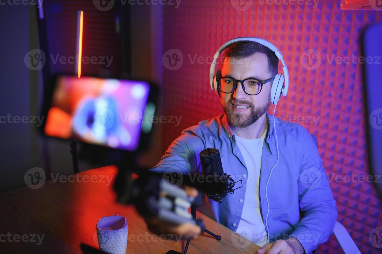 Young man recording or streaming podcast using microphone at his small broadcast studio. Content creator. photo