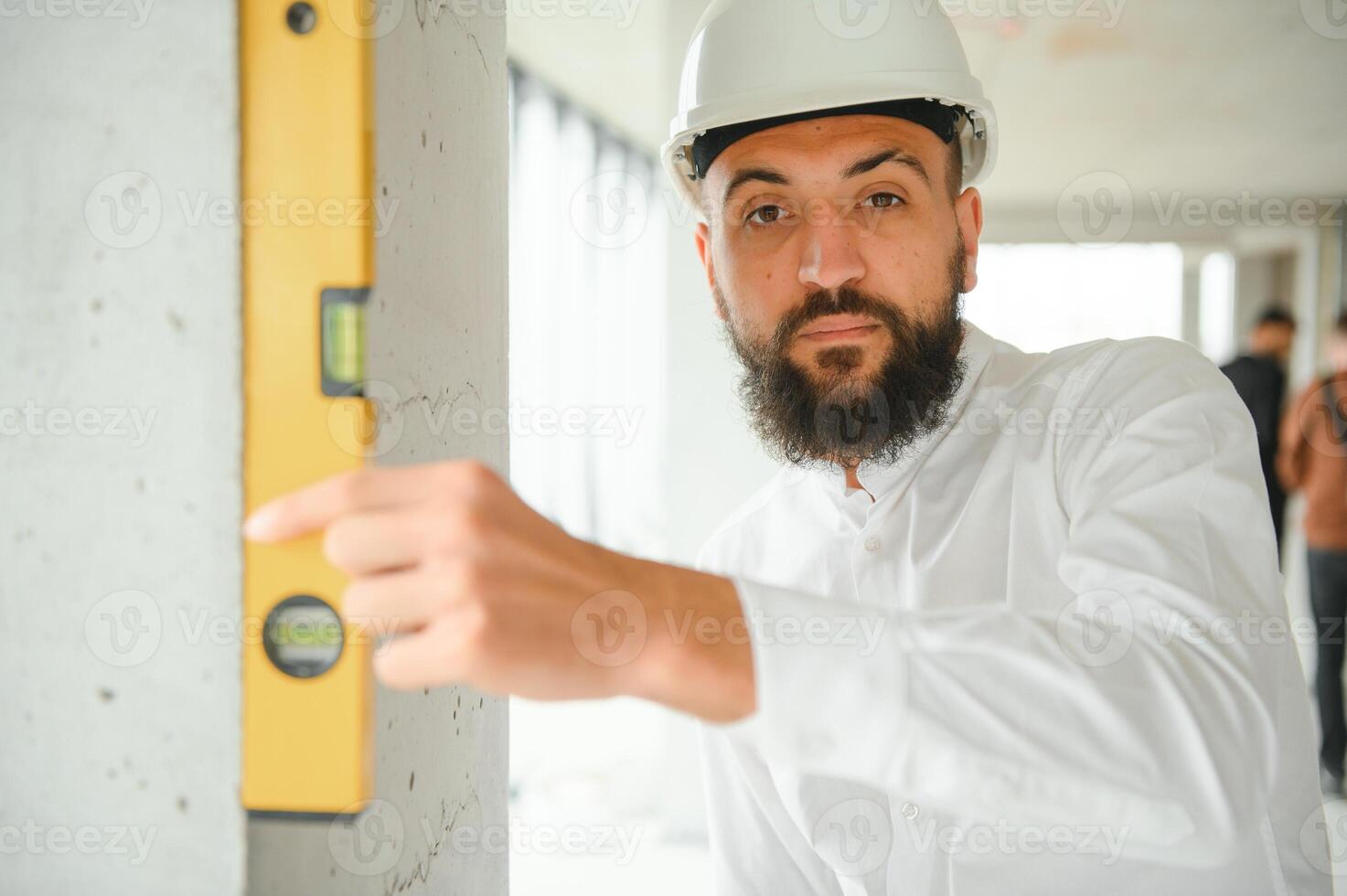 Serious busy young attractive arabic industrial engineer in hard hat with project drawings in factory interior. Professional and industry, builder architect job, worker checking work at plant indoor photo