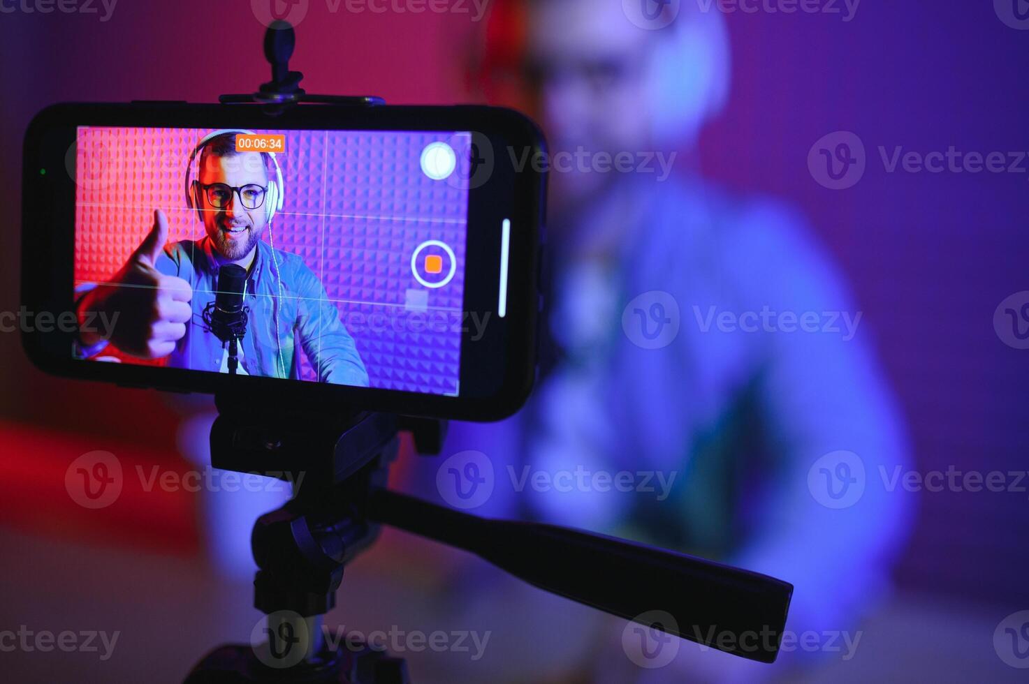 Young man recording or streaming podcast using microphone at his small broadcast studio. Content creator. photo