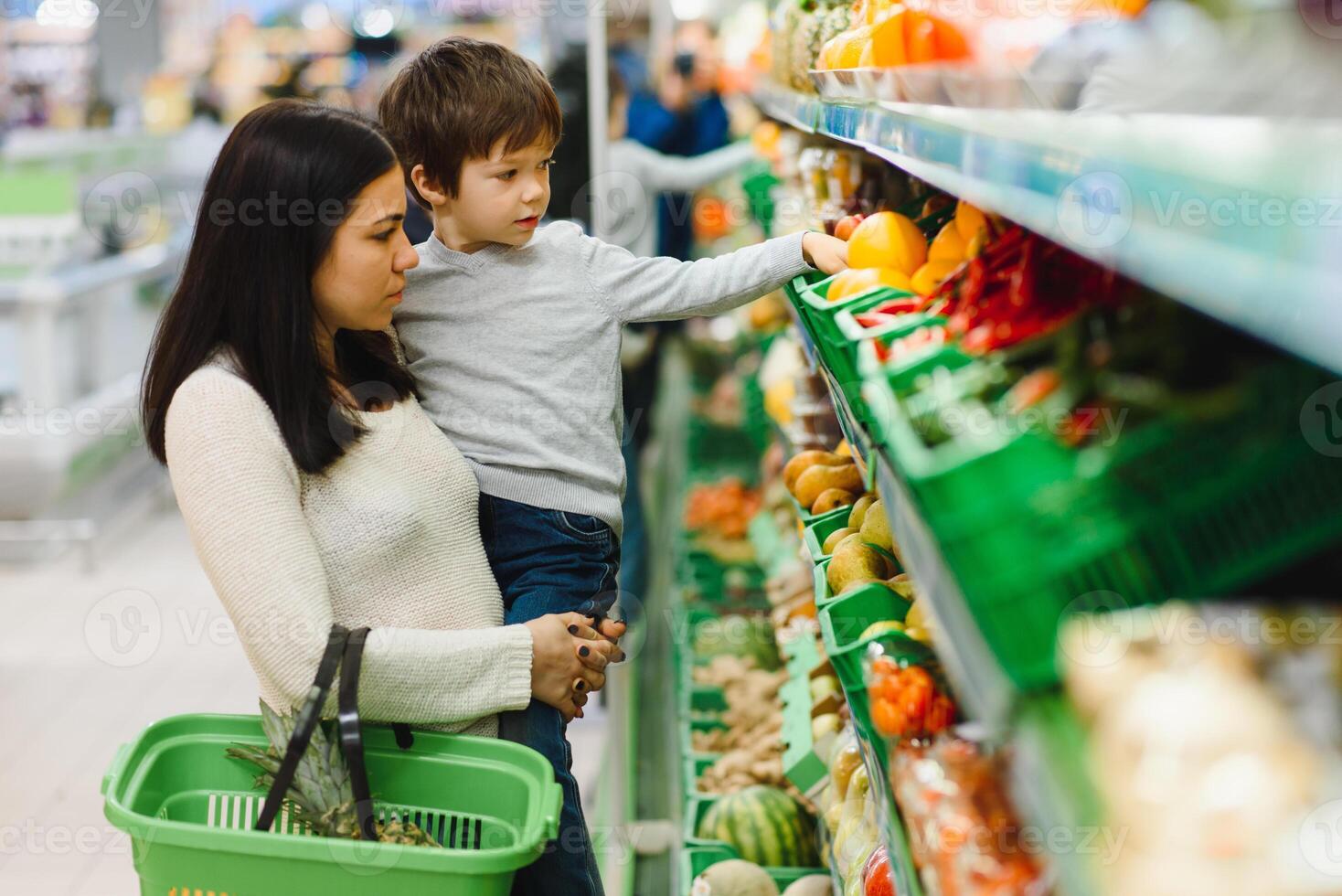 woman and child boy during family shopping with trolley at supermarket photo