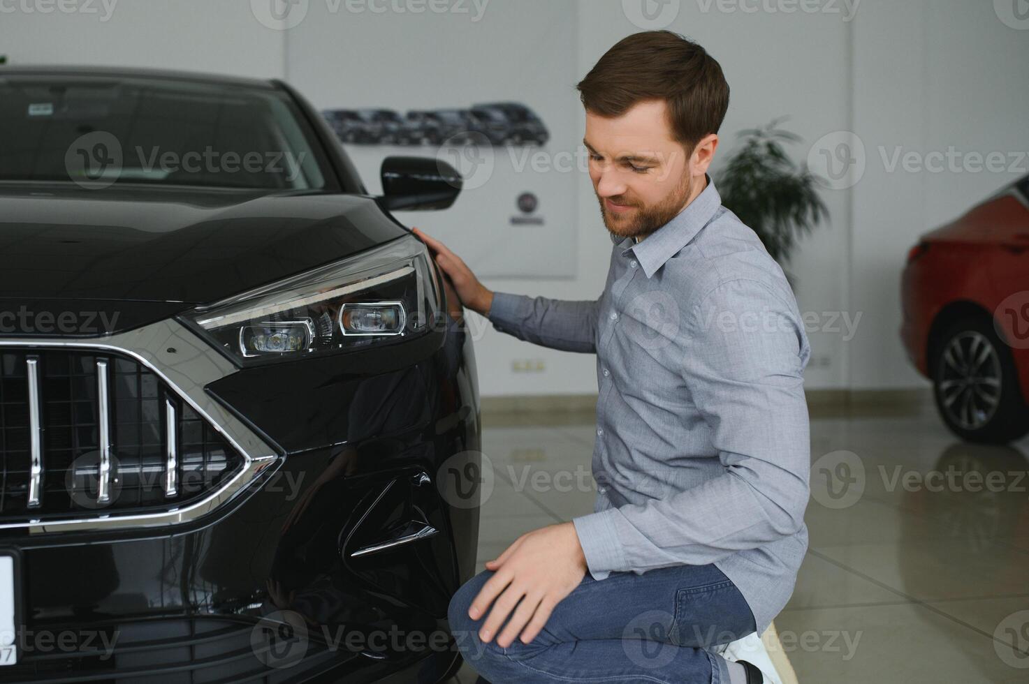 Young man is choosing a new vehicle in car dealership. photo