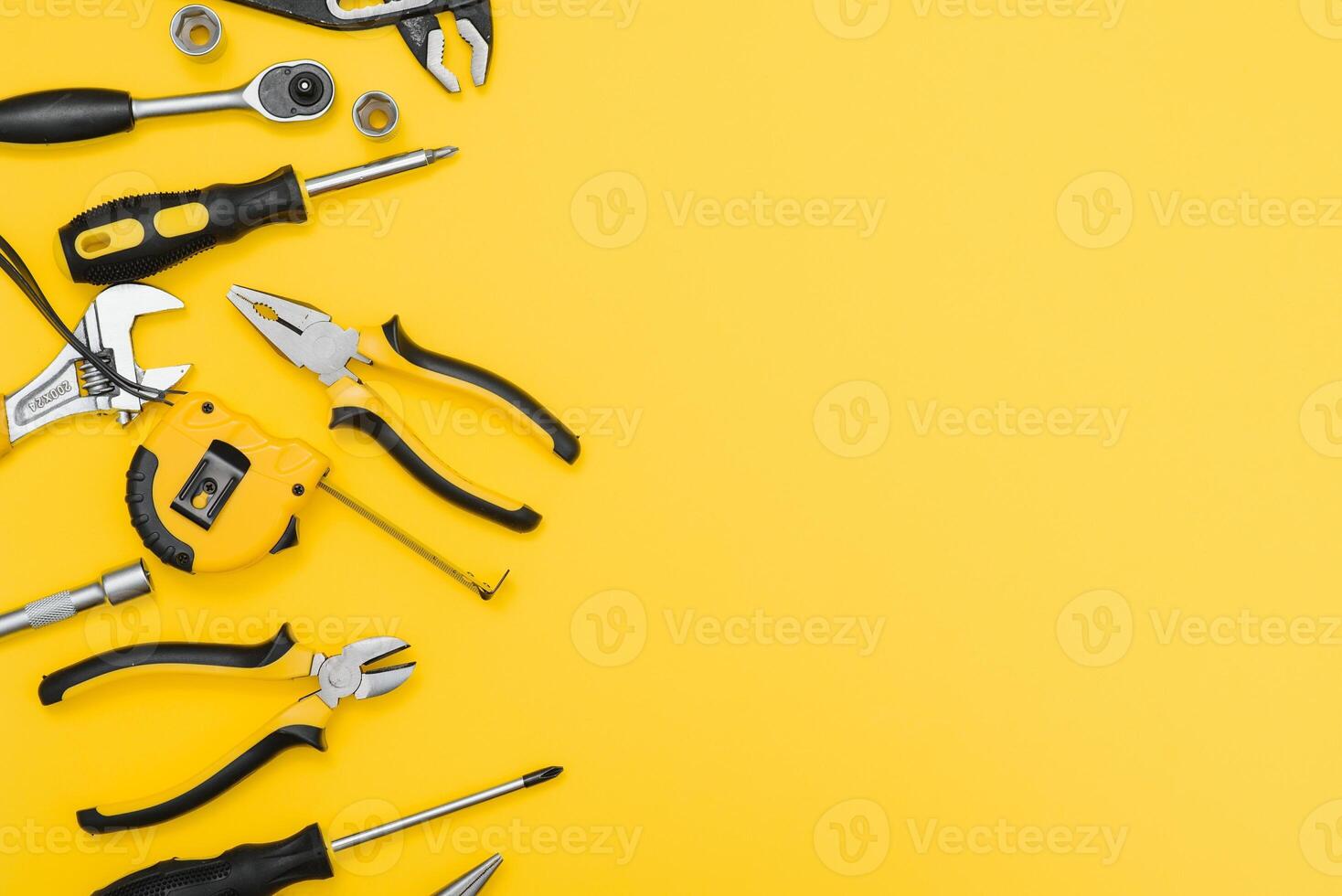 Yellow and black handy tools pilers and screwdriver isolated on yellow background photo