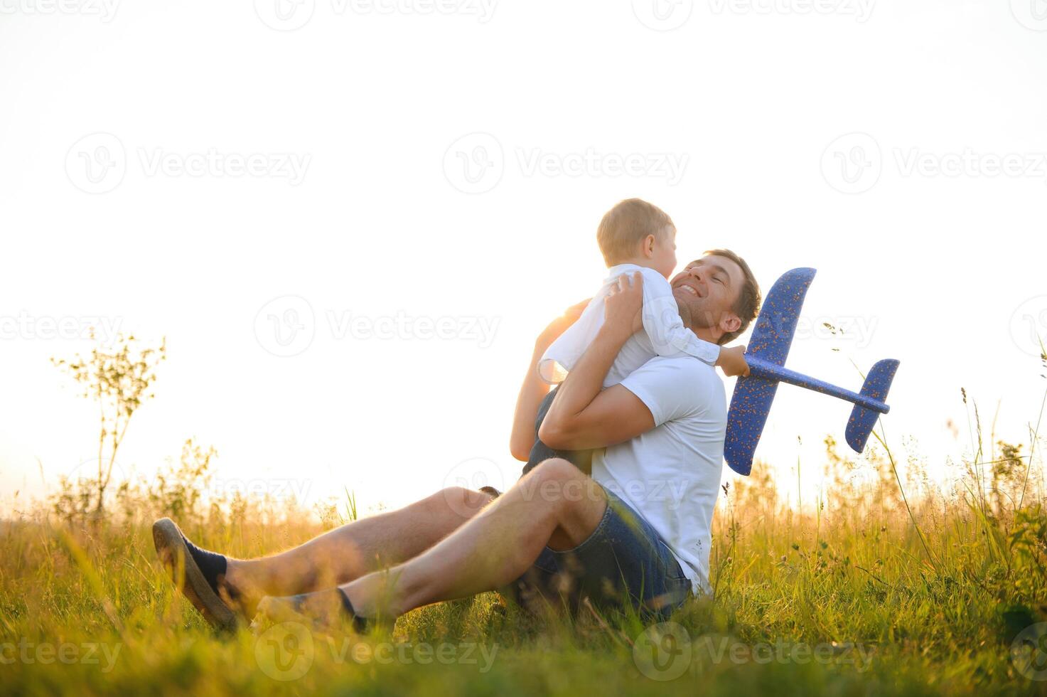 contento padre niño momento. padre llevar a cuestas su chico a puesta de sol mientras él es jugando con juguete avión. foto