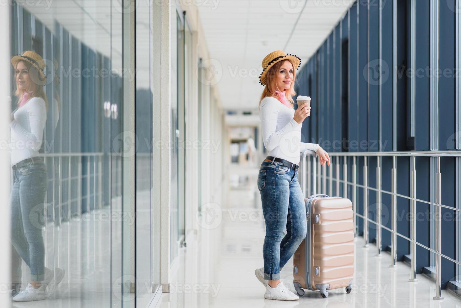 retrato de exitoso negocio mujer de viaje con caso a aeropuerto. hermosa elegante hembra viaje con equipaje. mujer esperando para avión y Bebiendo café foto