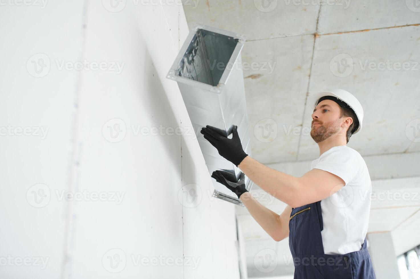 Industrial Theme. Warehouse Heating and Cooling System Installation by Professional Caucasian Technician. Commercial Building Ventilation Rectangle Canals. Air Distribution. photo