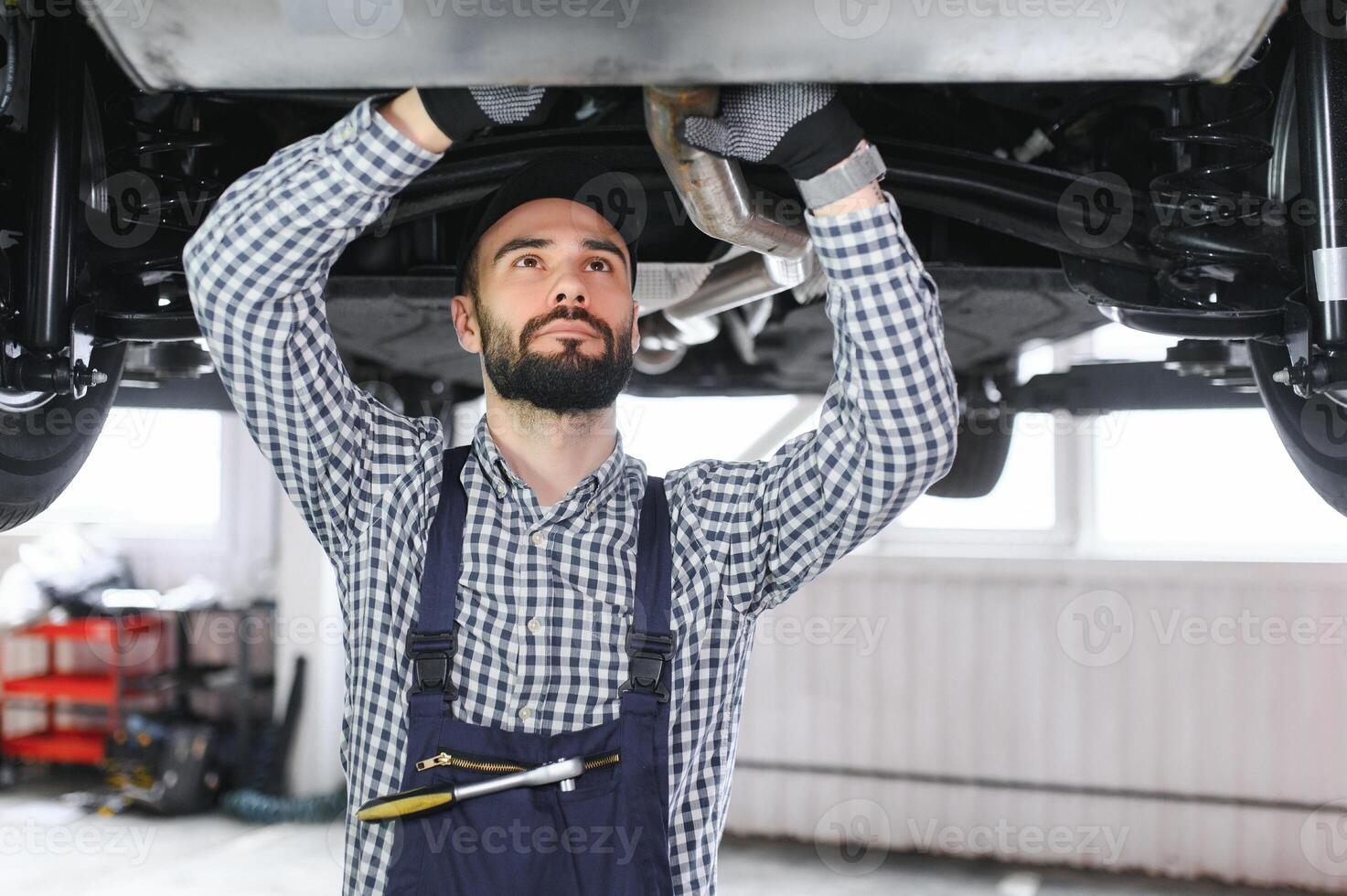 Portrait of a mechanic repairing a lifted car photo