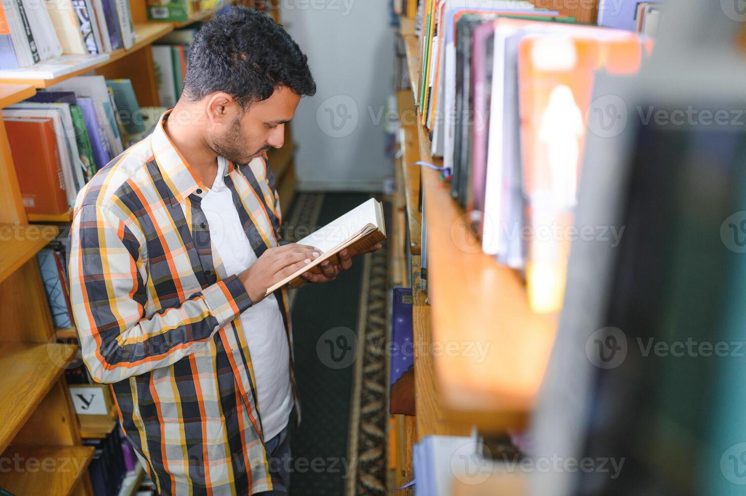 Happy smart indian or arabian guy, mixed race male, university student, in the library photo