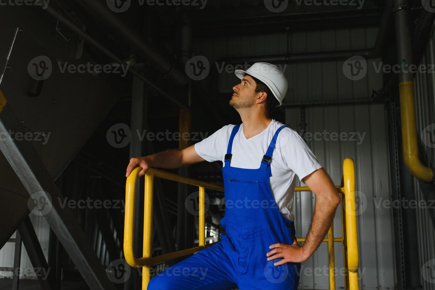 un joven hermoso empleado de un moderno fábrica en un blanco duro. en el antecedentes es un grande tienda para el producción. foto