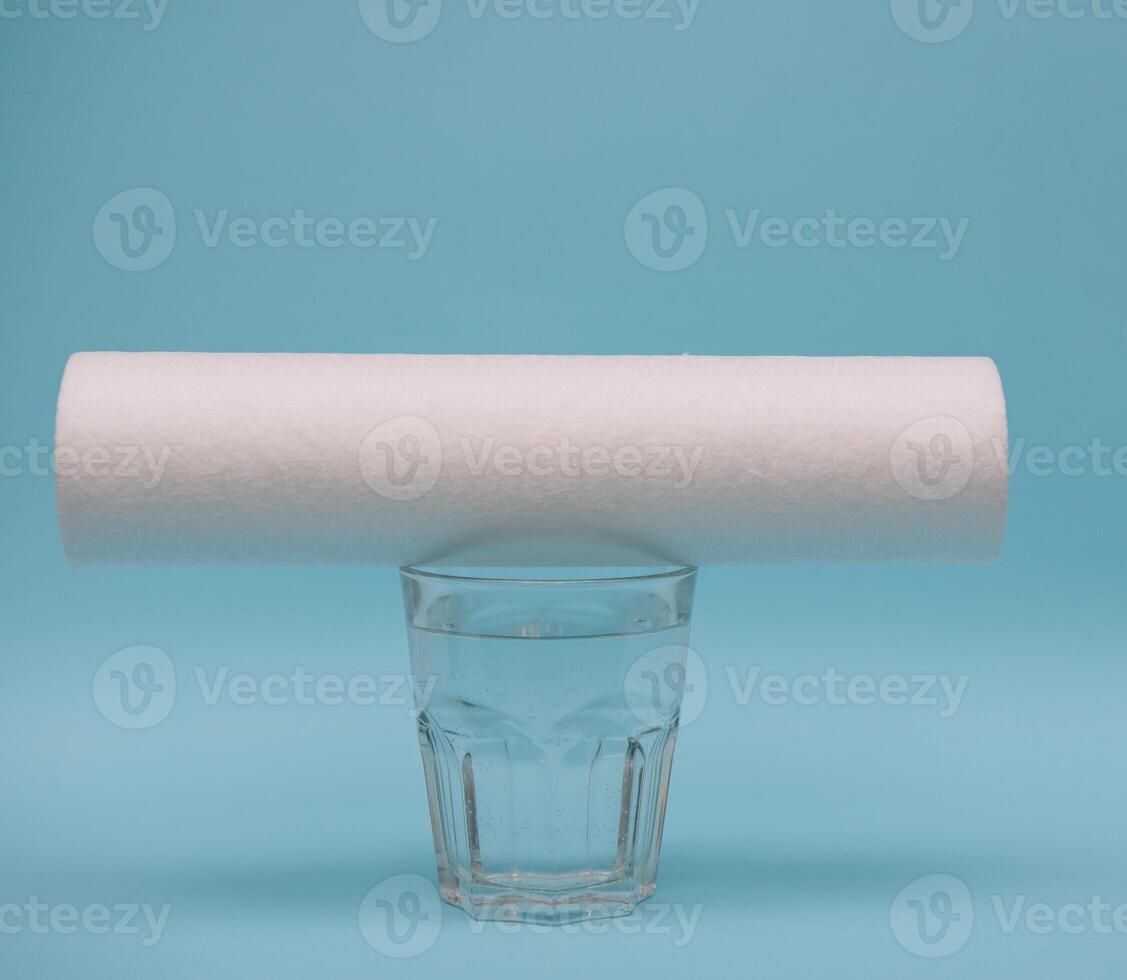 Water filters. Carbon cartridges and a glass on a blue background. Household filtration system. photo