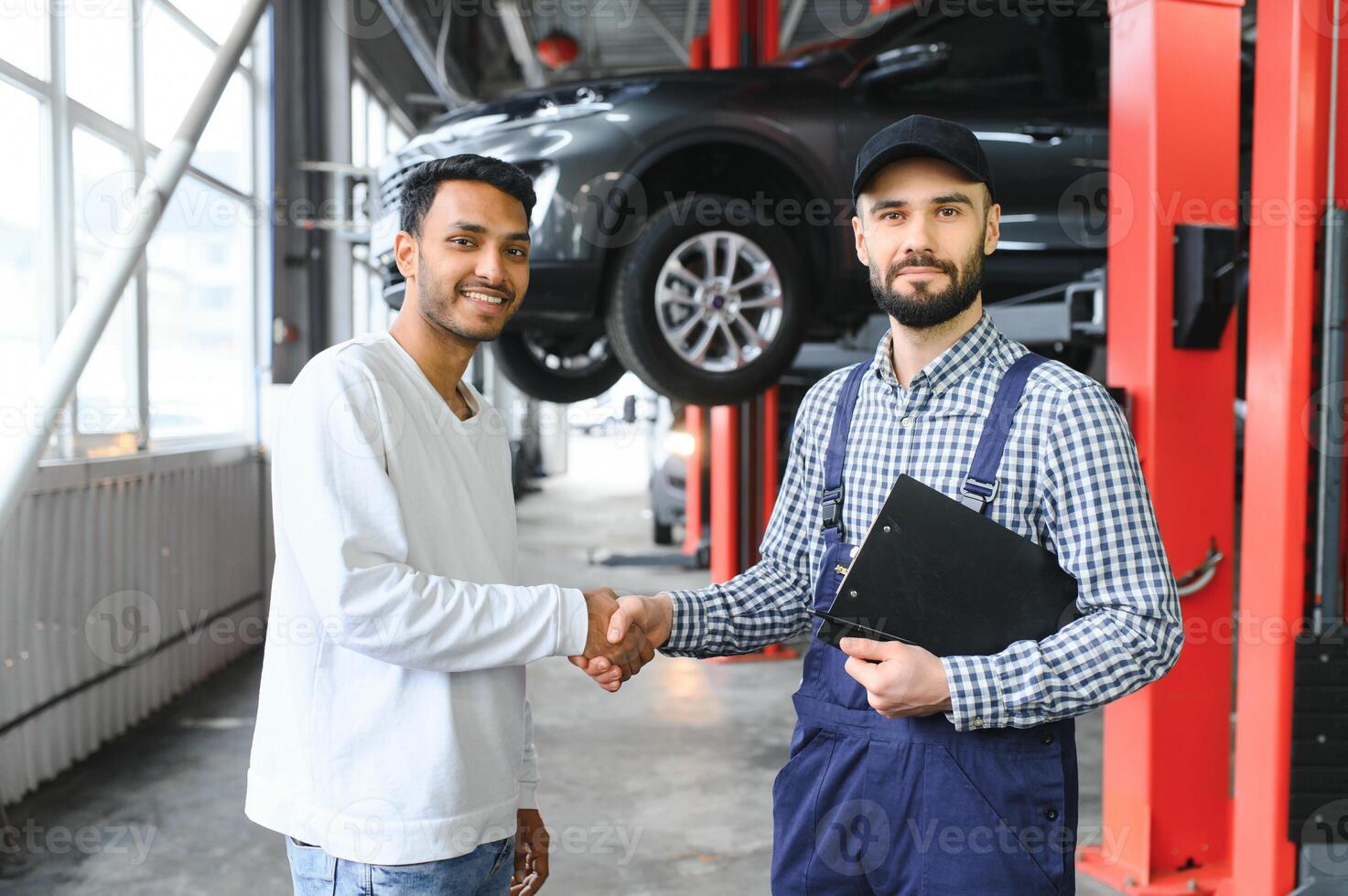 A mechanic in a car service repairs an Indian man's car. Car service concept photo