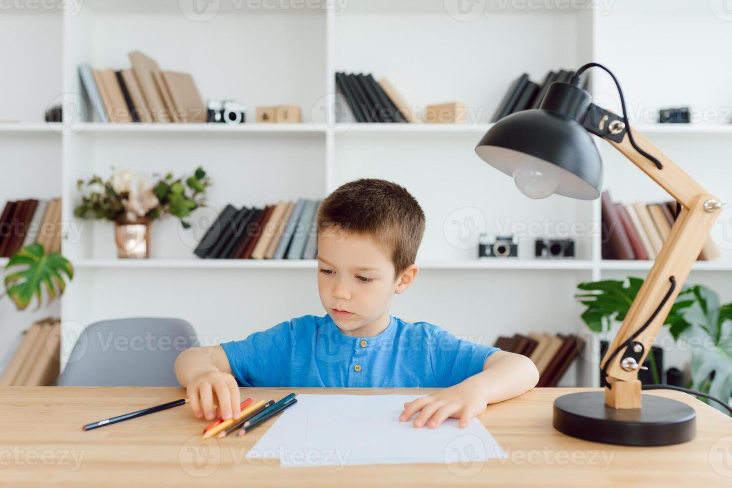 education, childhood, people, homework and school concept - smiling student boy with book writing to notebook at home photo