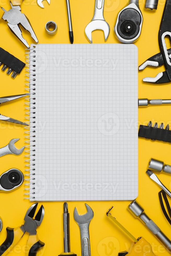 Tools top view on yellow background. Plier, open wrenches, screwdrivers and staple gun flat lay with copy space photo