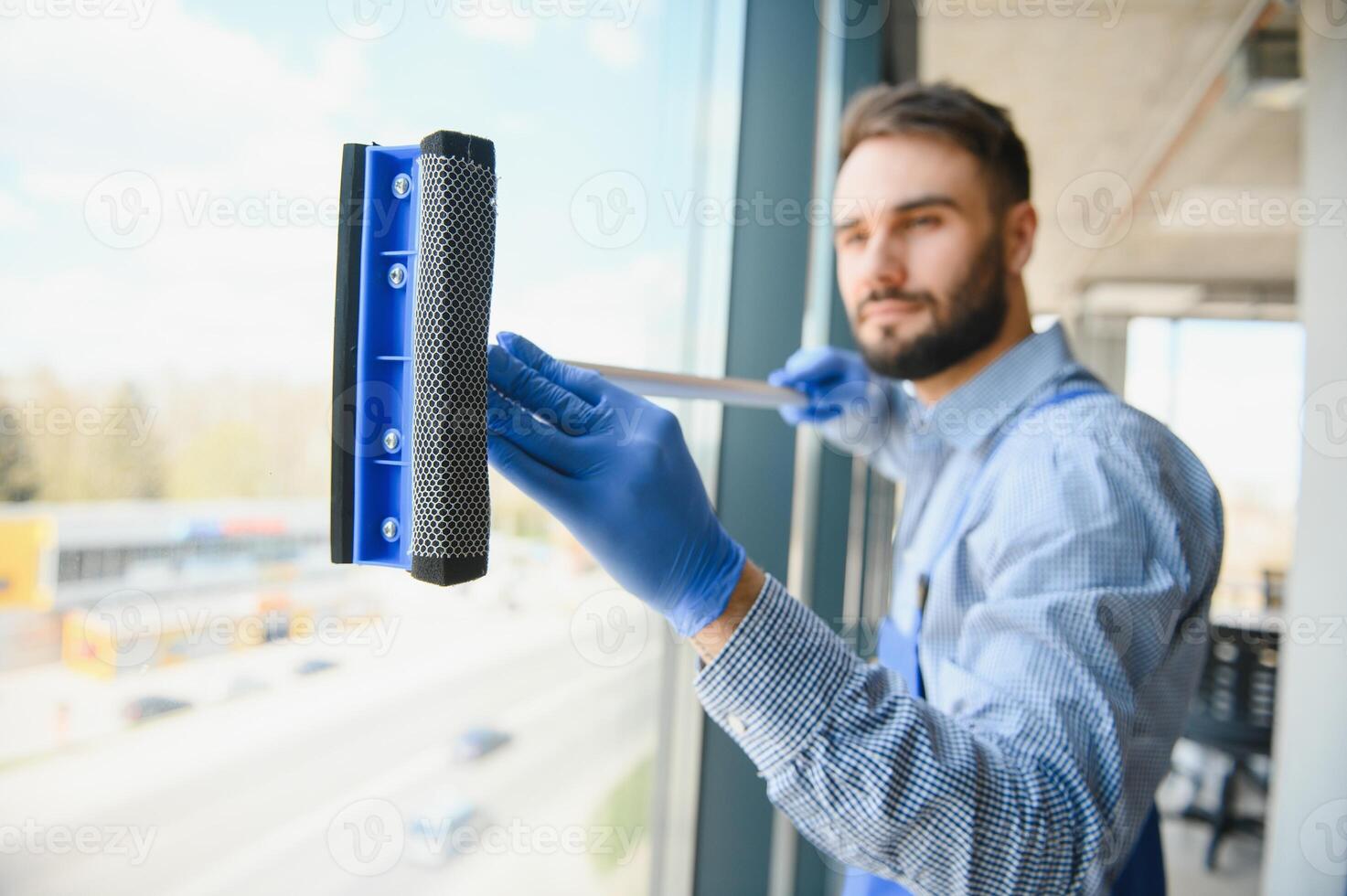 Male janitor cleaning window in office photo