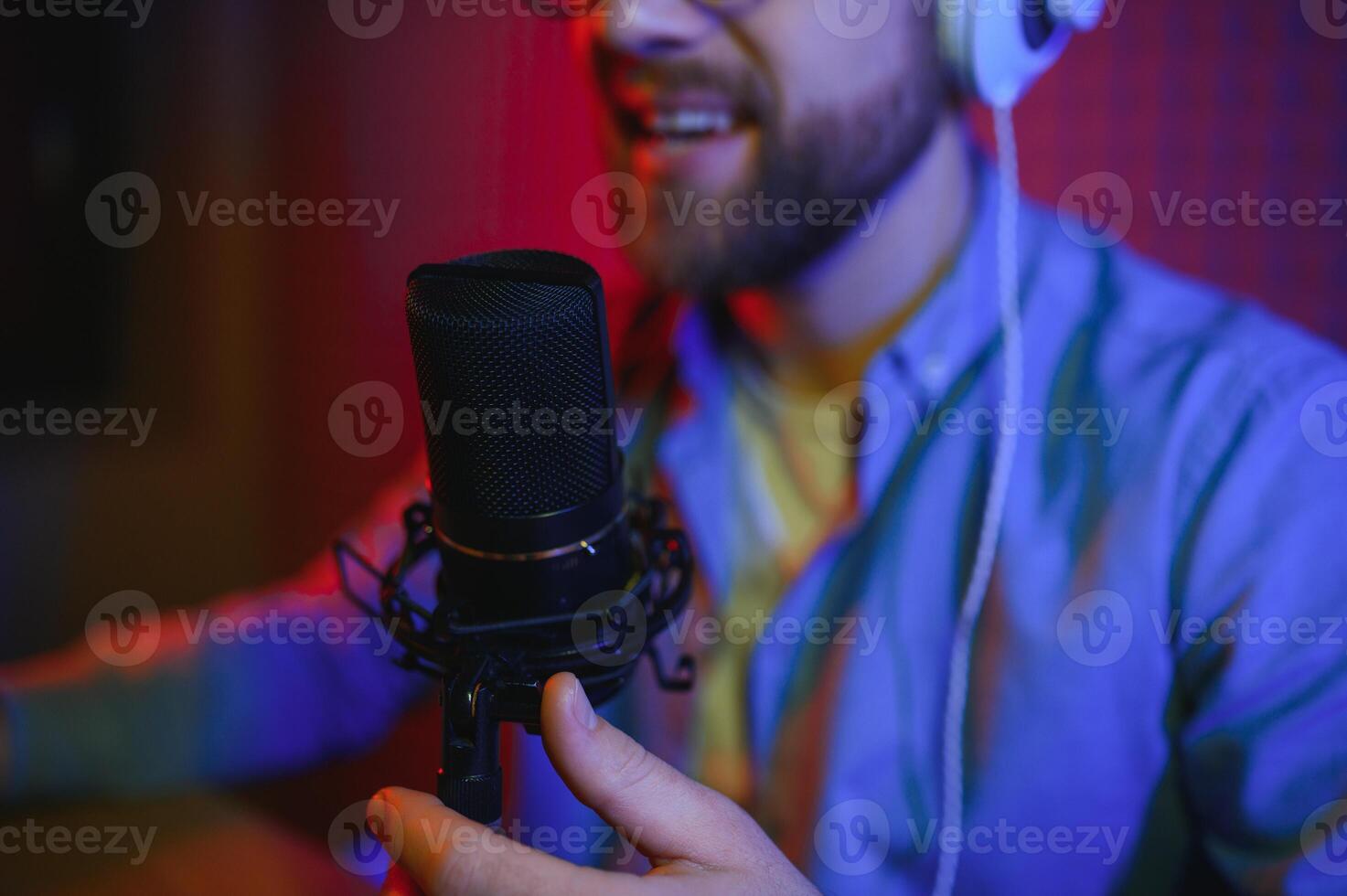 Male radio host with headphones on head and mic in studio reading news or broadcast show, toned photo