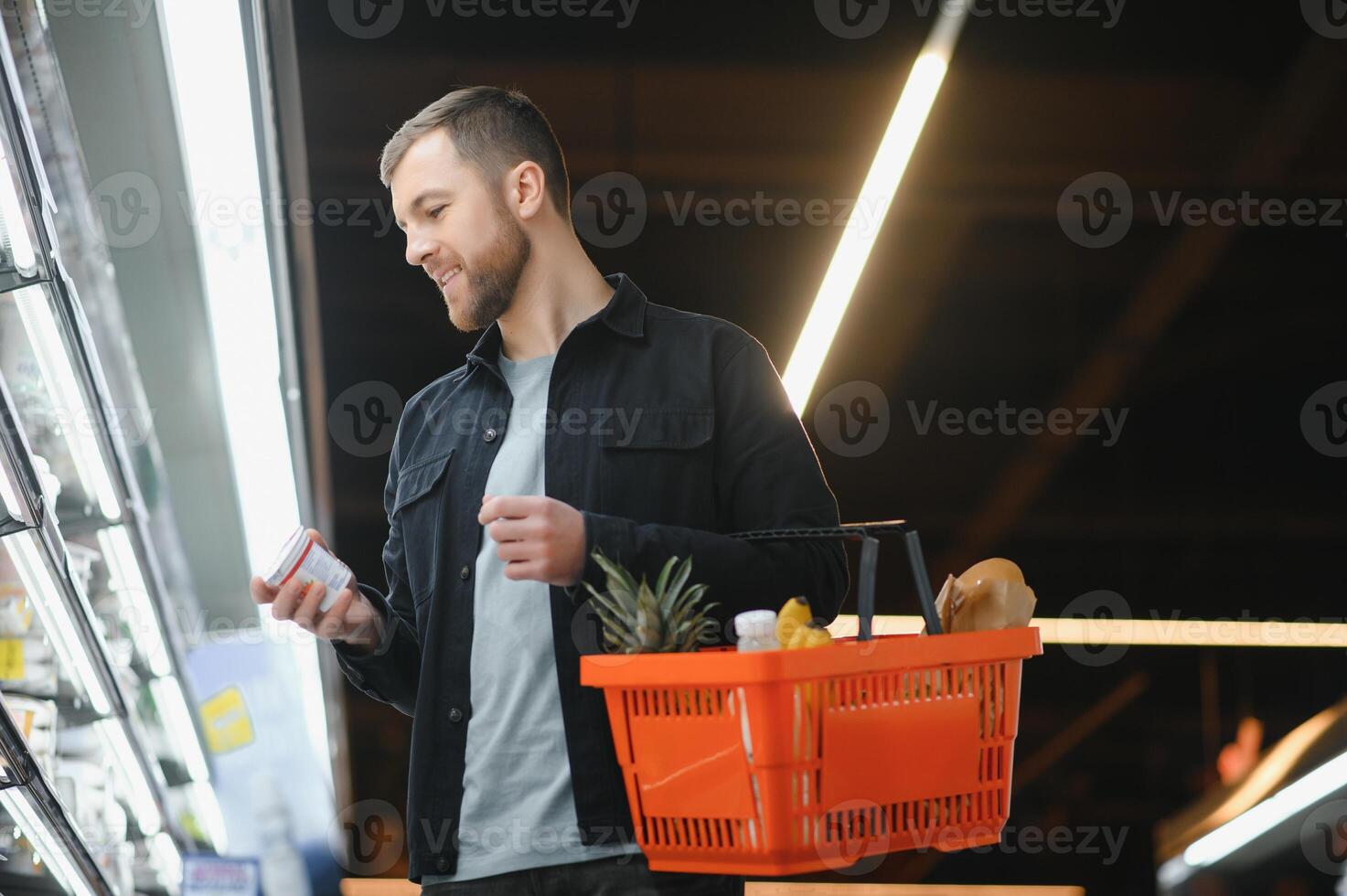 Young man buying groceries at the supermarket. Other customers in background. Consumerism concept. photo