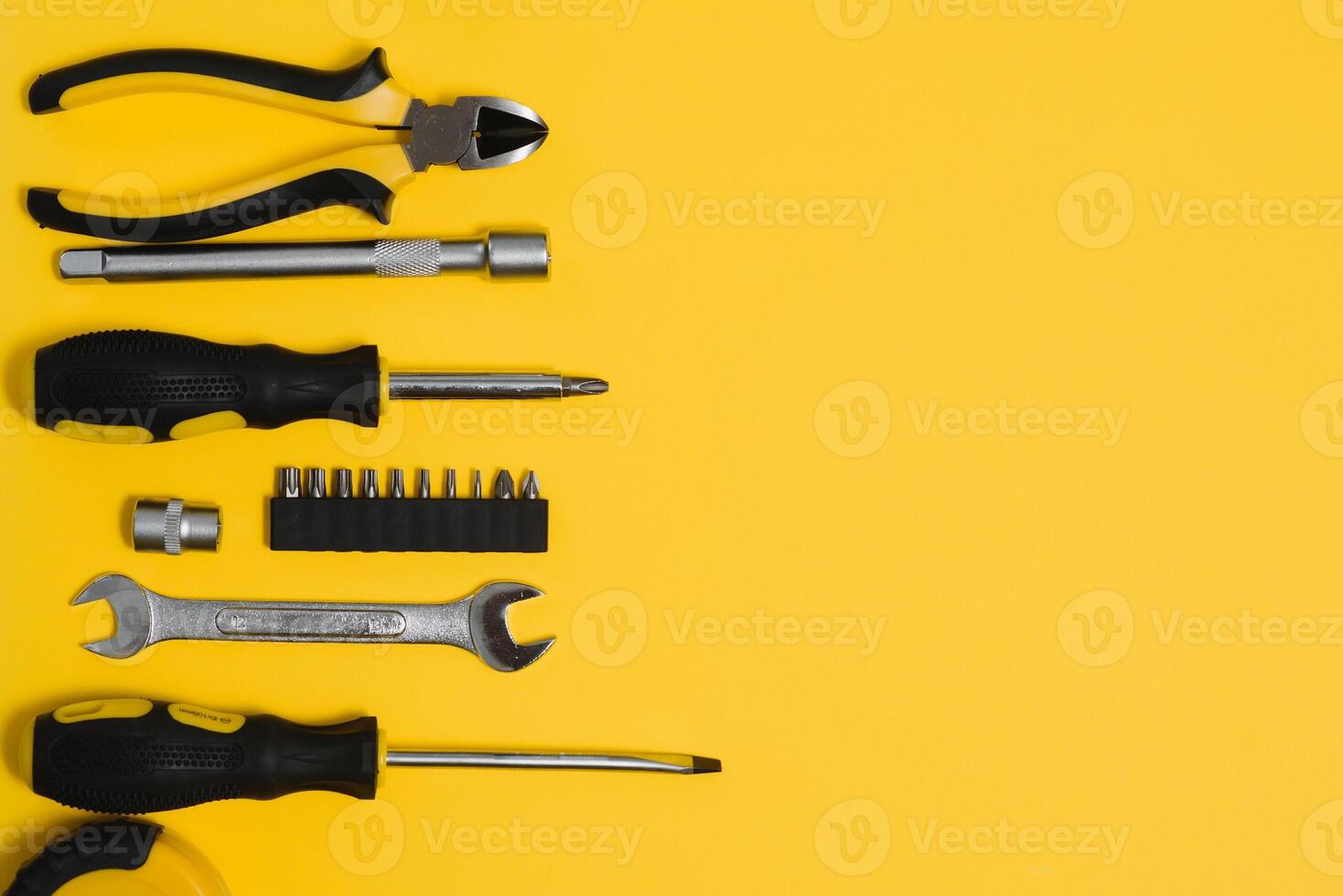 Yellow and black handy tools pilers and screwdriver isolated on yellow background. photo