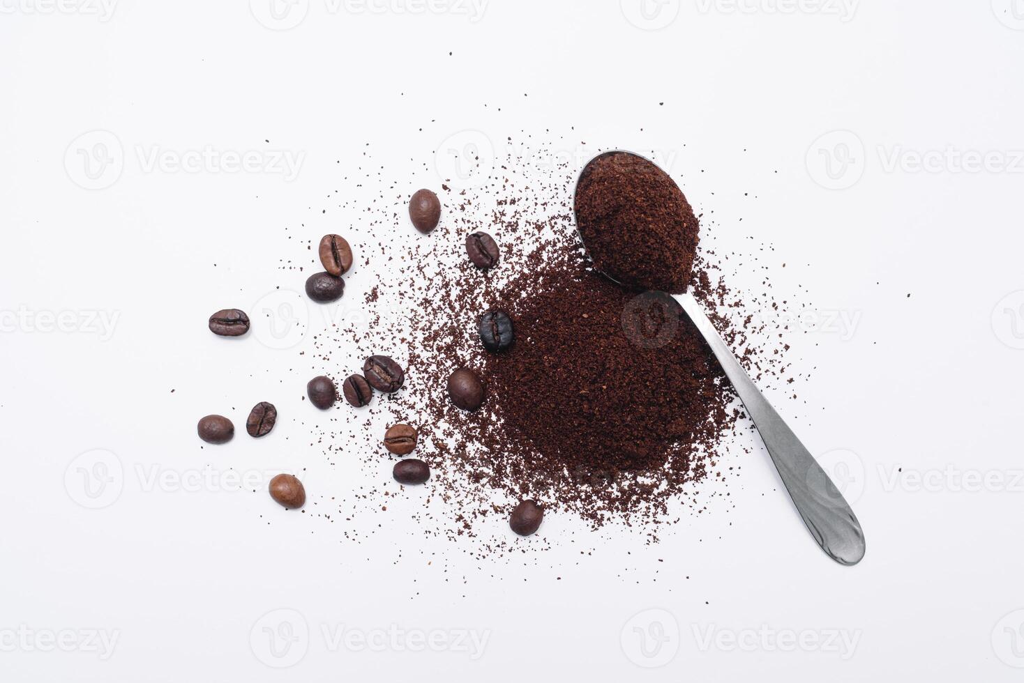 Grounded coffee in a spoon surrounded with beans isolated photo