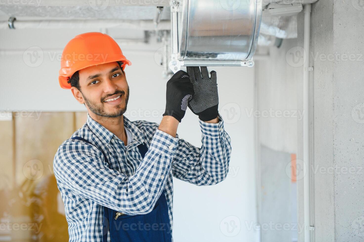 hvac indian worker install ducted pipe system for ventilation and air conditioning. copy space photo