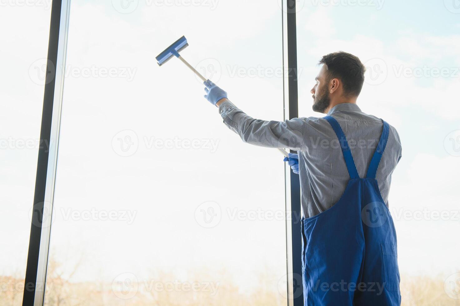 joven limpiando ventana en la oficina foto