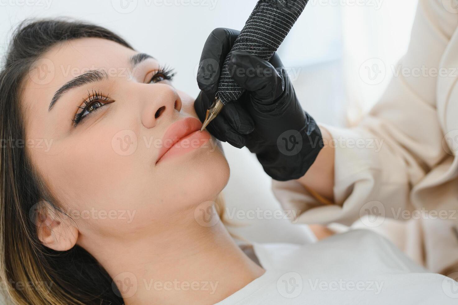 Healthy Spa Young Beautiful Woman Having Permanent Make-up on her Lips. Close-up photo