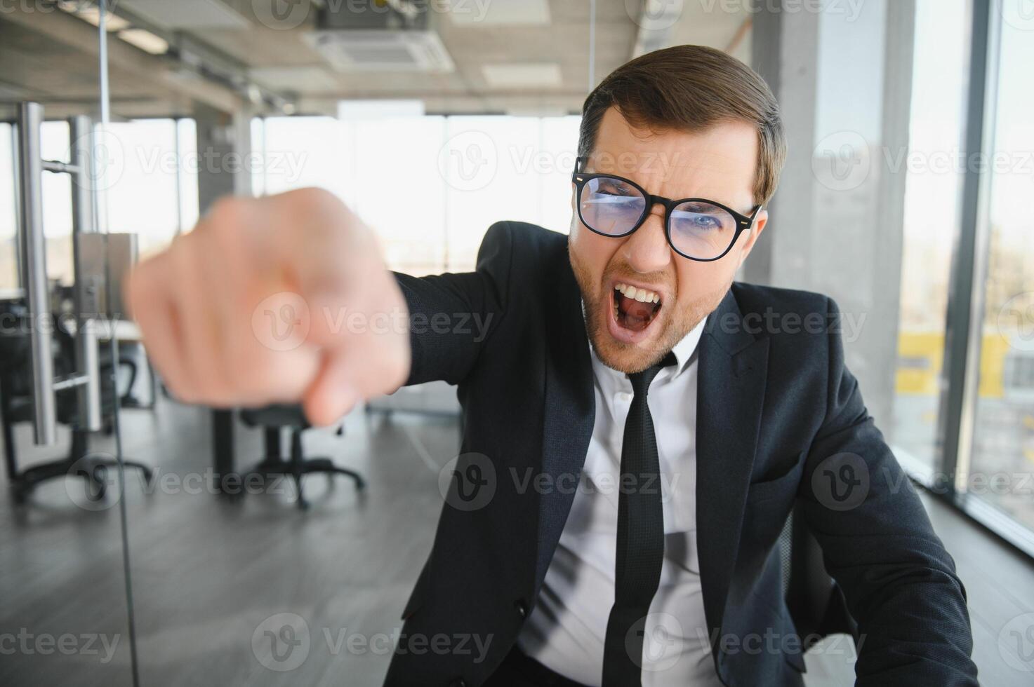 Angry senior businessman sitting at his desk and screaming photo