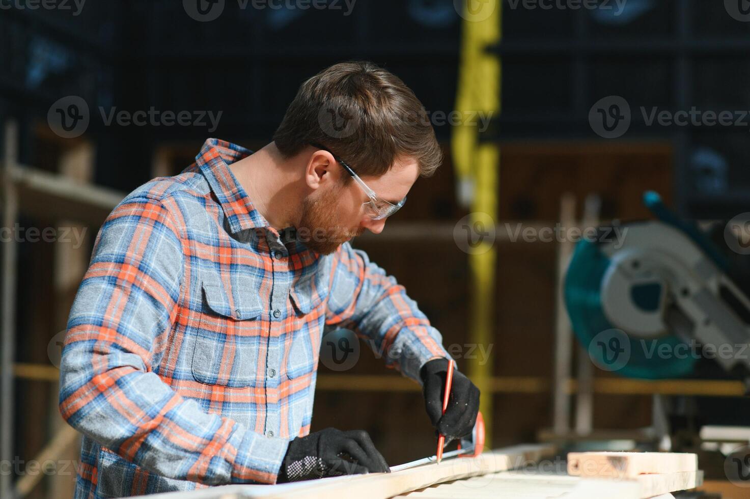 Wood cutting table with electric circular saw. Professional carpenter in uniform cutting wooden board at sawmill carpentry manufacturing . Sawing machine photo