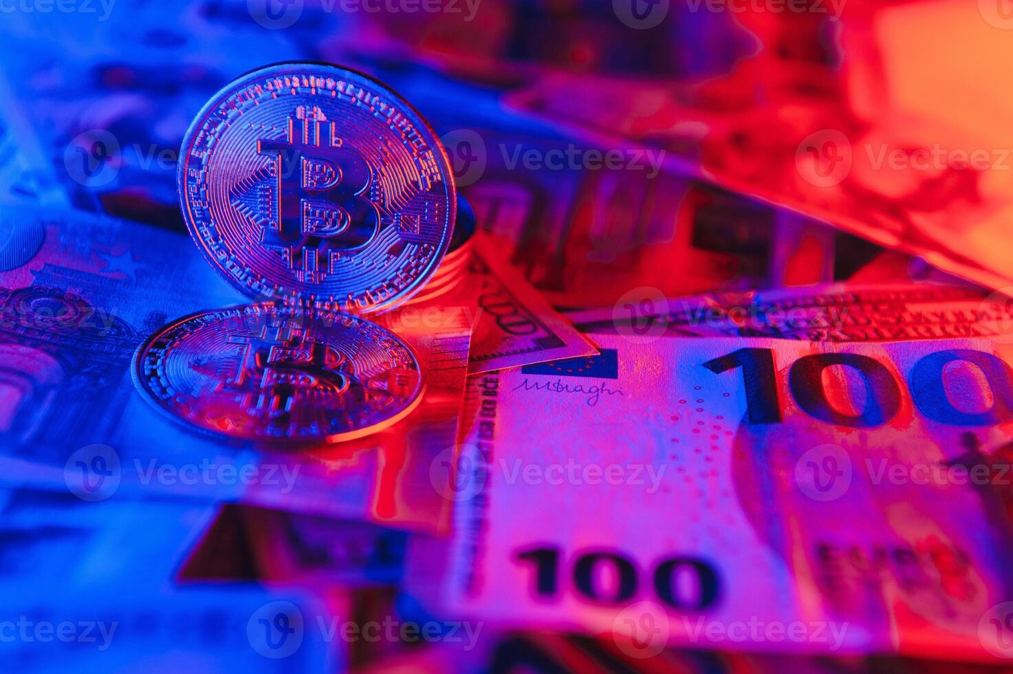 Close up heap of golden bitcoin physical coins on top of Euro, dollar banknotes background, high angle view, selective focus photo