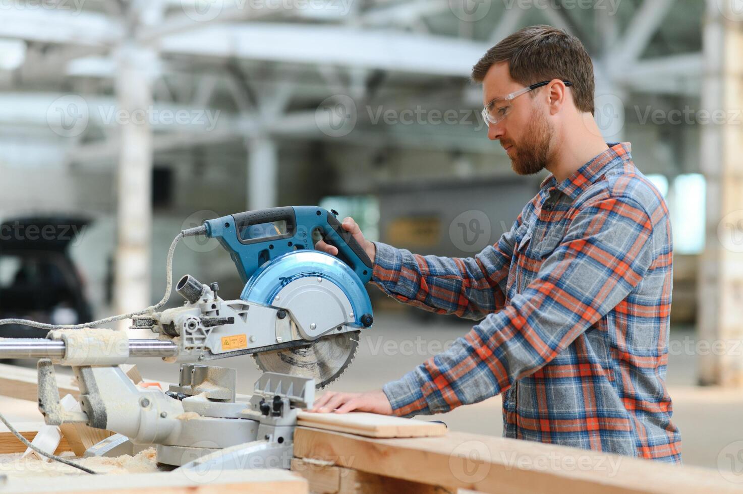 Closeup professional carpenter hold electric circular saw at sawmill. Skilled joiner using circular saw for cutting wood board at woodworking workshop. Furniture production factory. Man cabinet maker photo