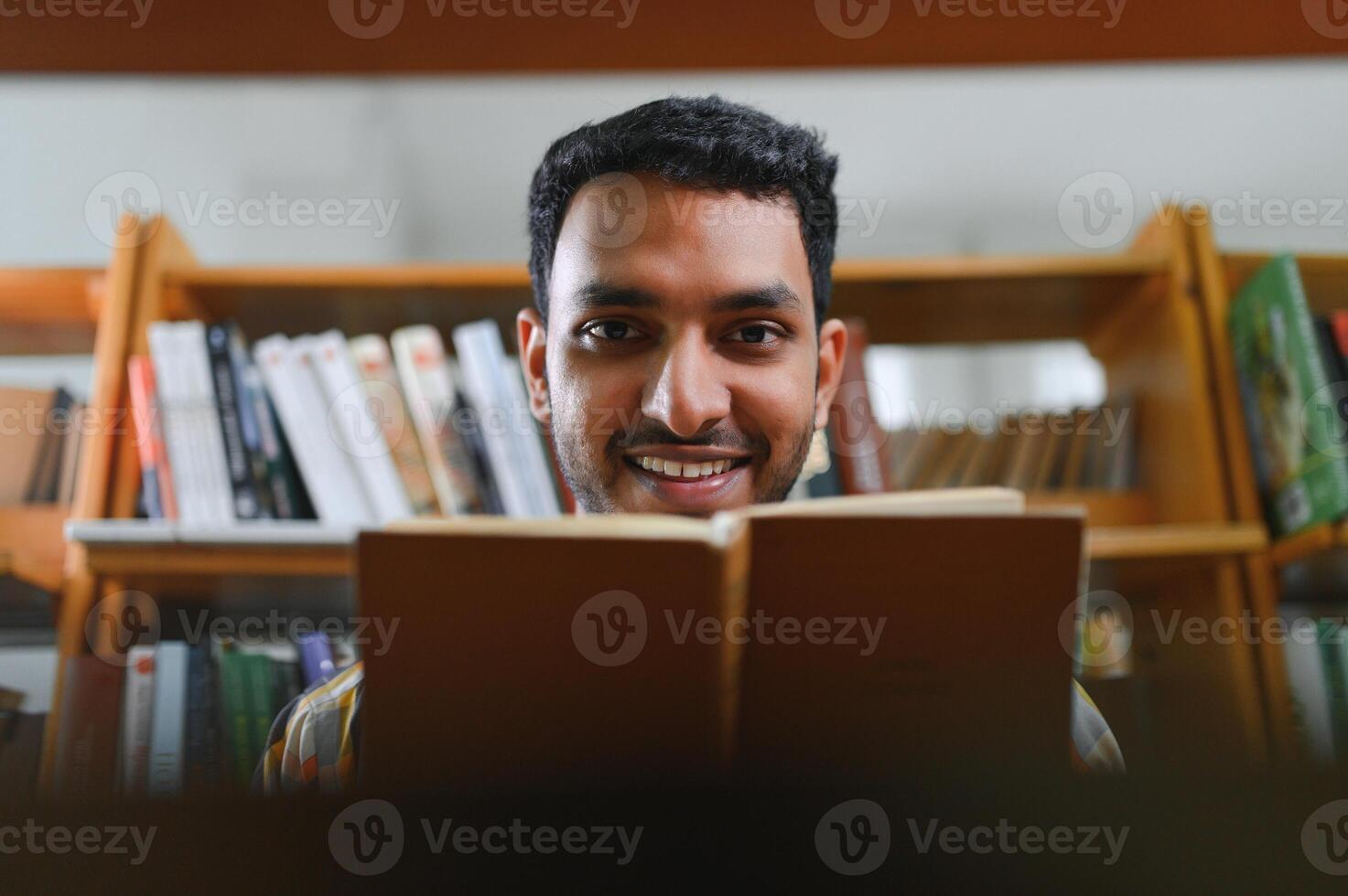 Happy smart indian or arabian guy, mixed race male, university student, in the library photo