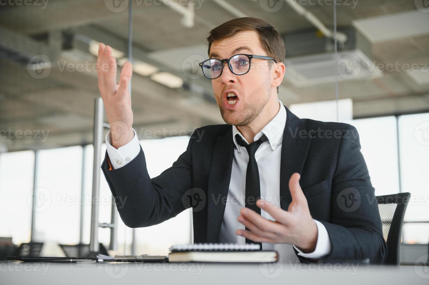 Angry businessman sitting at the table and screaming. photo