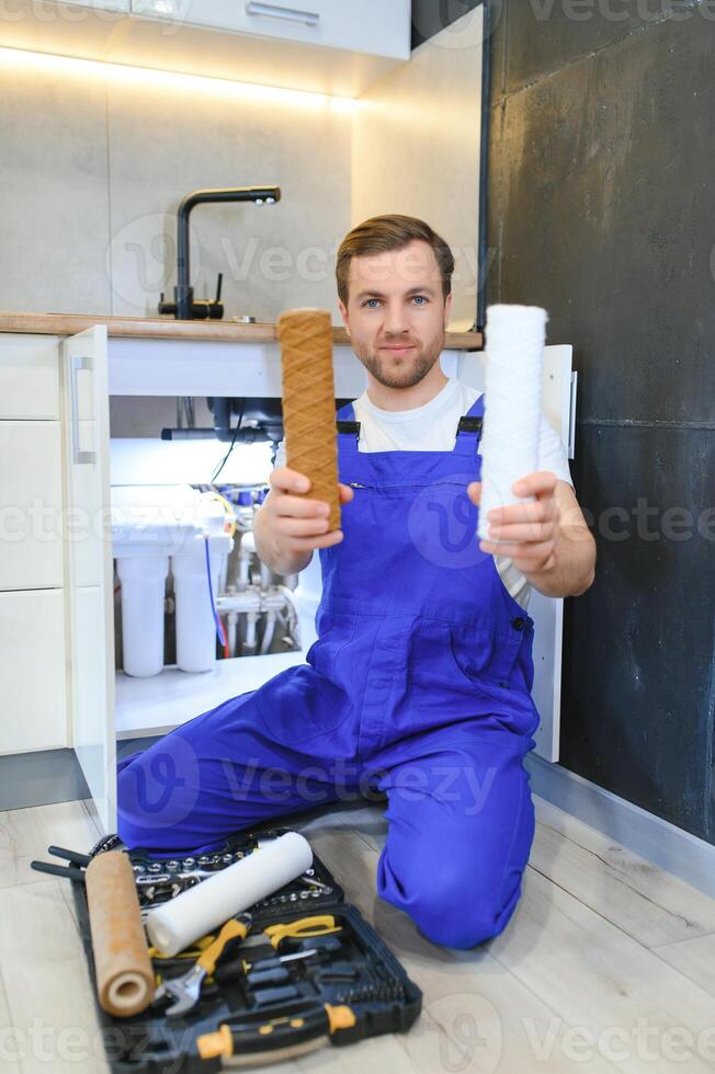 Plumber working change cartridge filter for water in kitchen. Concept filtration system. photo