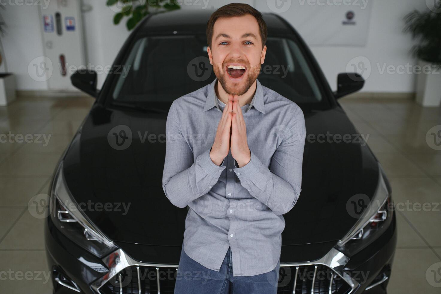 Visiting car dealership. Handsome bearded man is stroking his new car and smiling photo