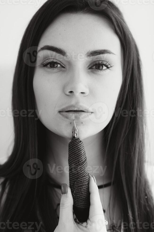 Permanent makeup master with a machine for permanent makeup in his hands. Woman with tattoo pen. photo