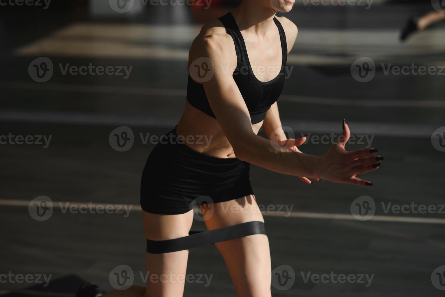 Athletic girl doing exercise for glute with resistance band on gray background. Fitness woman working out photo