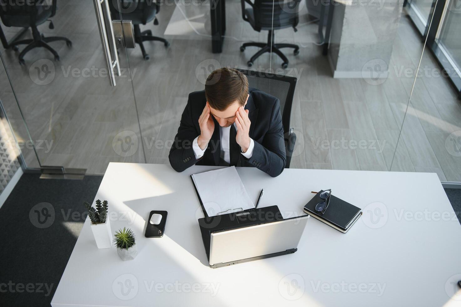 Depressed young businessman holding head in hands, has problem, a laptop on the desk. A guy made a mistake in a work photo